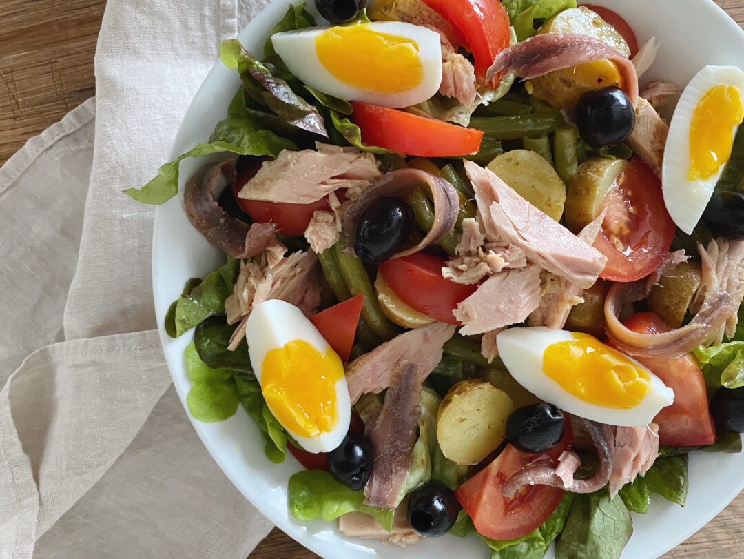 Salade Niçoise mit Sardellen, Thon, Eiern und Oliven in einer weissen Schüssel serviert